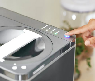 Hand pushing start button on FoodCycler machine