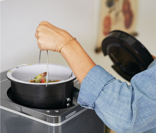 Hand lifting bucket out of FoodCycler Machine