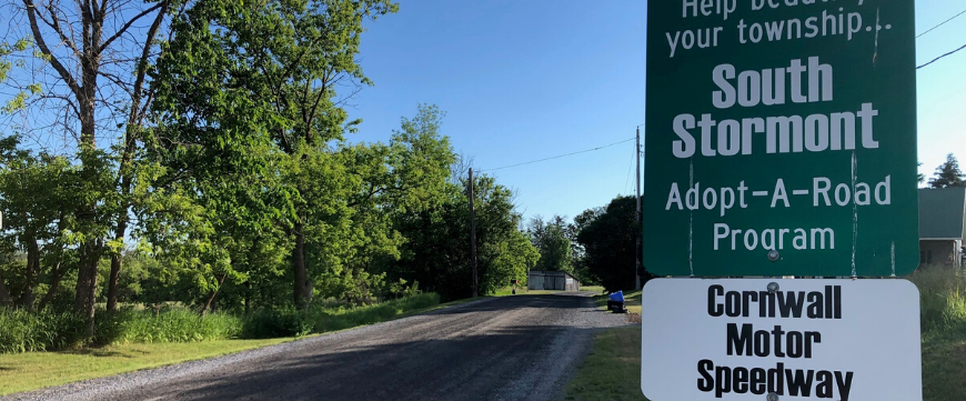 Road with a sign for Adopt a Road program