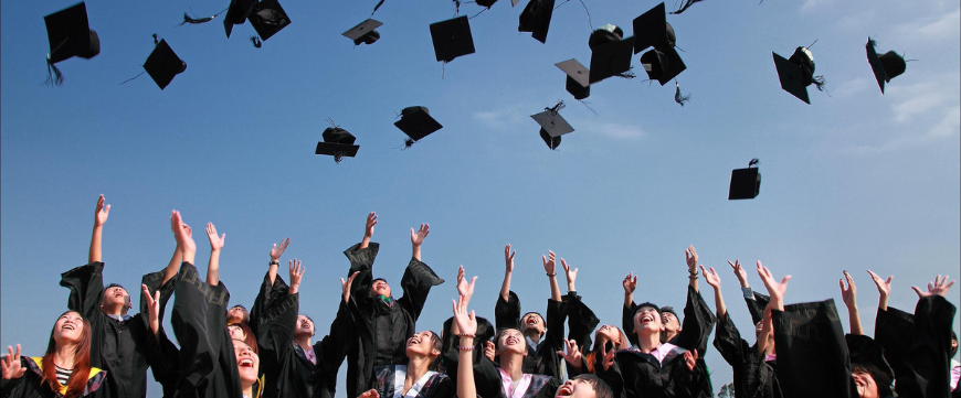 Graduating students throwing graduation caps in the air