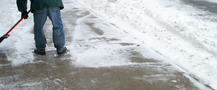 Sidewalk in the winter with man shoveling snow off