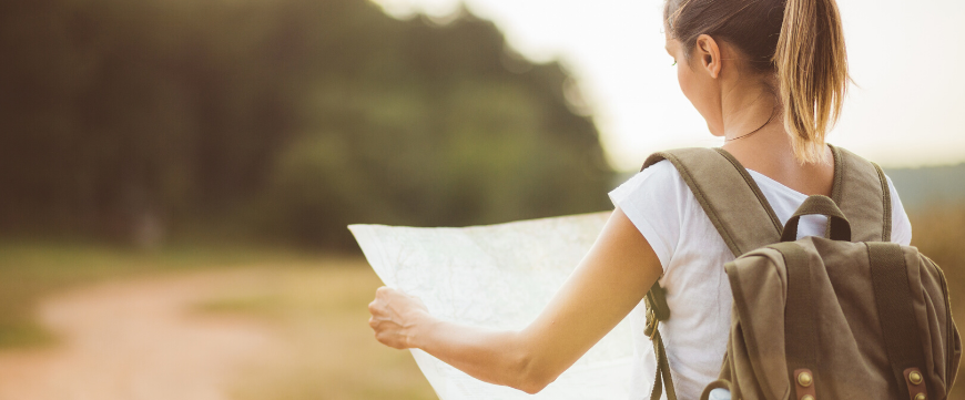 Woman Holding Map on Dirt Road