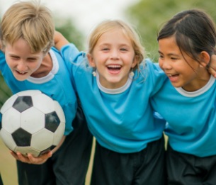 Kids holding one another and a soccer ball