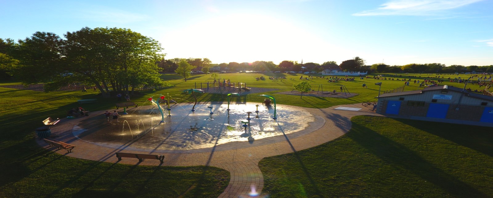 Overhead photo of splash pad with children playing in the park in the distance