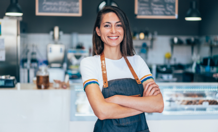 Woman in apron standing in front of cafe