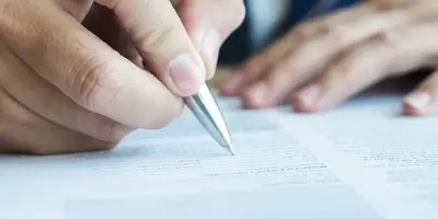 hands signing a document with pen