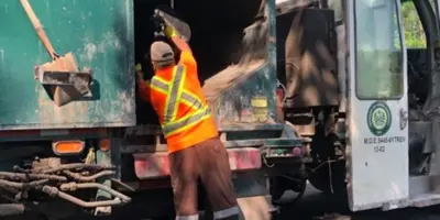 Garbage man throwing garbage into garbage truck